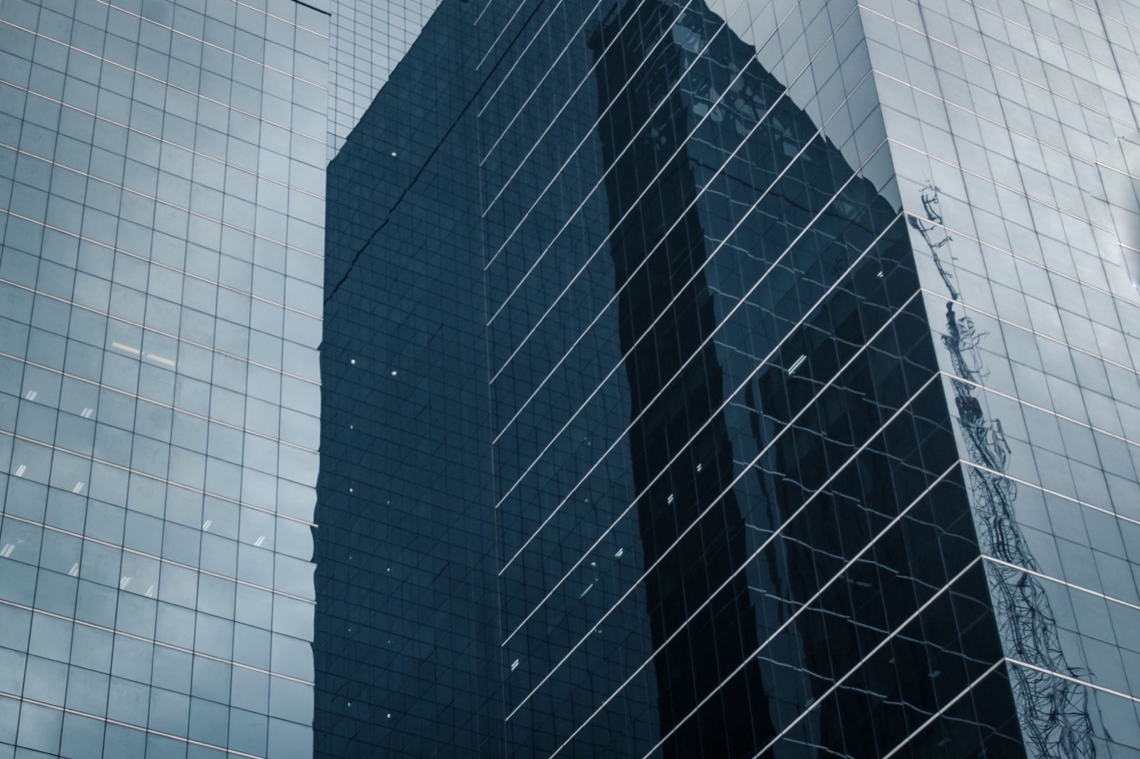 A dark glass facade reflecting the building opposite.